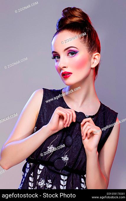 Beautiful young woman with hairdo and bright purple tone make-up. Doll style. Beauty shot on grey background. Copy space