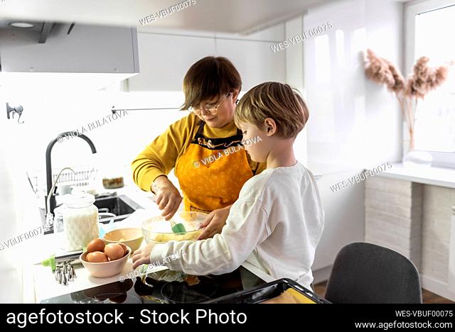 Grandmother with grandson cooking in kitchen at home