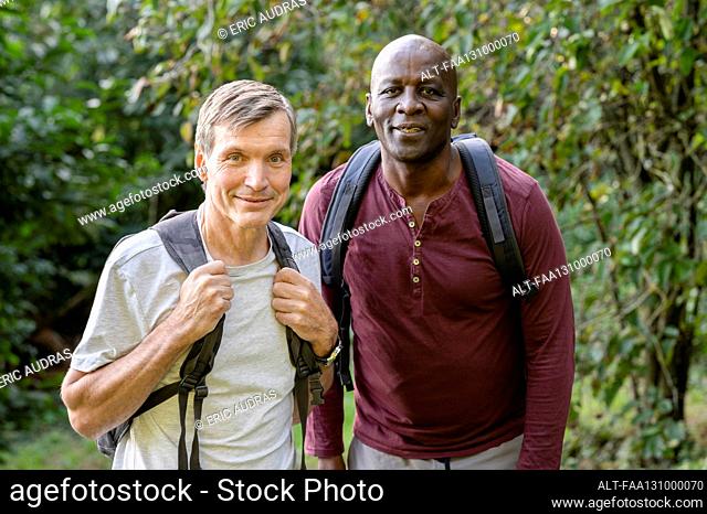 Two male friends hiking in the woods stop to take a picture