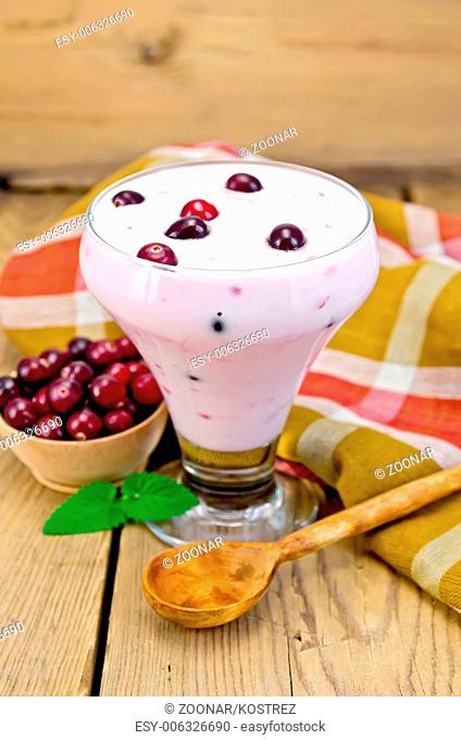 Yogurt thick with cranberries and spoon on the board