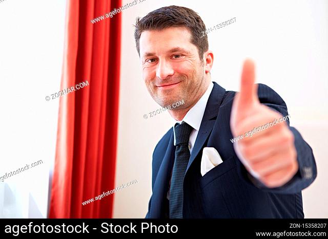 Zufriedener Geschäftsmann im Hotelzimmer hält seinen Daumen hoch