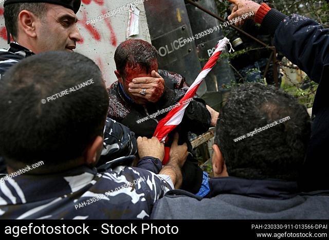 30 March 2023, Lebanon, Beirut: A Lebanese army retiree covers his face that is full by red pepper sprayed at him by riot police during his attempt to storm...