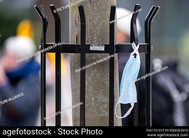 15 October 2020, Bavaria, Nuremberg: A used mouth-and-nose protector is hanging from a tree guard in the city centre. With stricter corona requirements