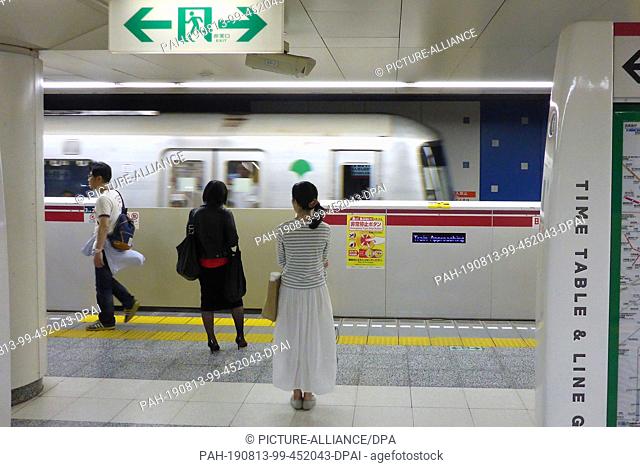 18 May 2018, Japan, Tokio: Passengers stand in front of a boarding safety system in Tokyo's subway, which separates the train from the track bed and thus...
