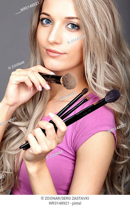 Blonde beauty female stylist - visagist with makeup brushes