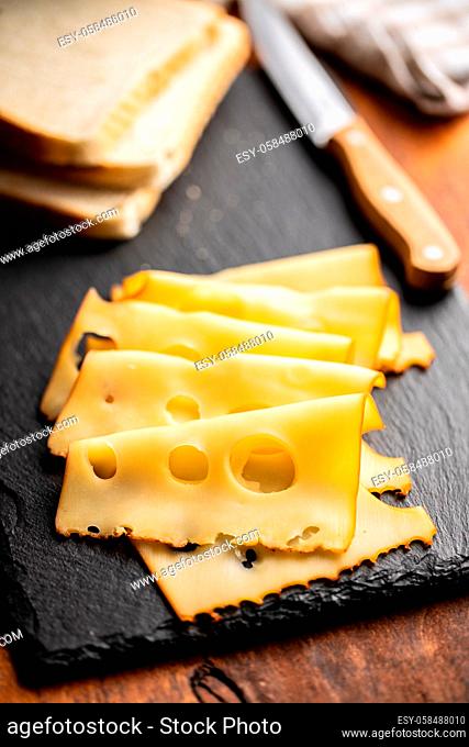 Sliced smoked hard cheese on cutting board