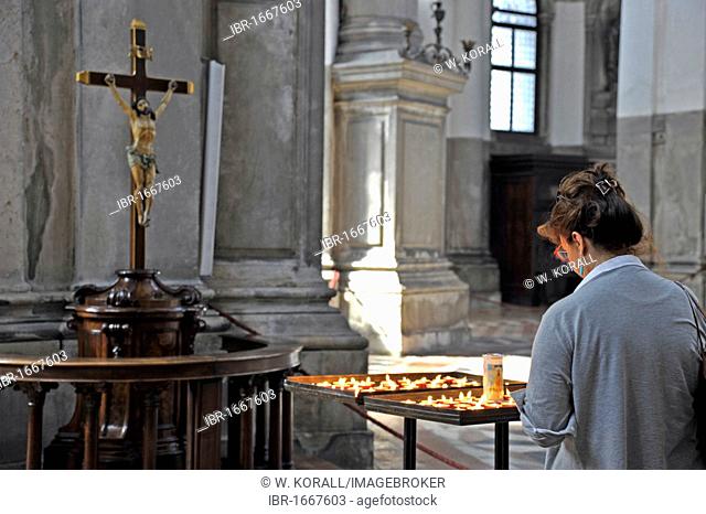 Woman in prayer with candles in front of Jesus on the cross in the nave of the Church of Santa Maria della Salute, Venezia, Venice, Italy, Europe