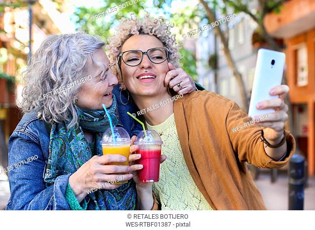 Senior mother with her adult daughter taking selfie in the city
