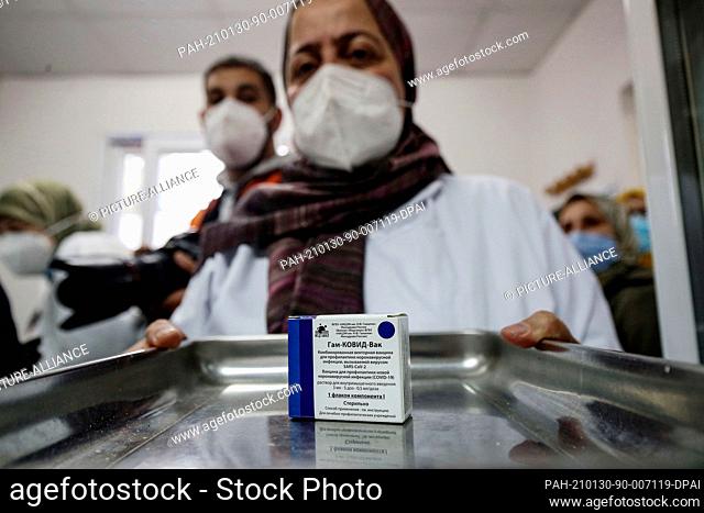 30 January 2021, Algeria, Blida: A medic carries a tray with a pack of vials containing the Russian-made Sputnik V COVID-19 vaccine at a clinic in Blida