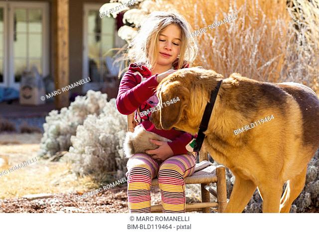 Caucasian girl petting dog outdoors