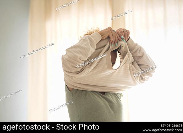 Unrecognizable female people wearing sweater getting ready at home - morning wake up adult woman with window light in background