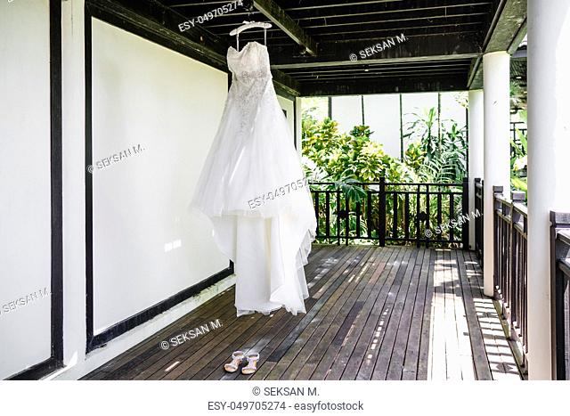 The wedding dress of the bride hanging at the terrace suring getting ready, luxury and gorgeous wedding gown