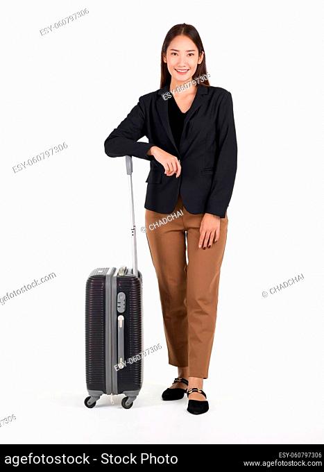 Young asian women in black suit smile and rest her arm on a black suitcase. Portrait on white background with studio light