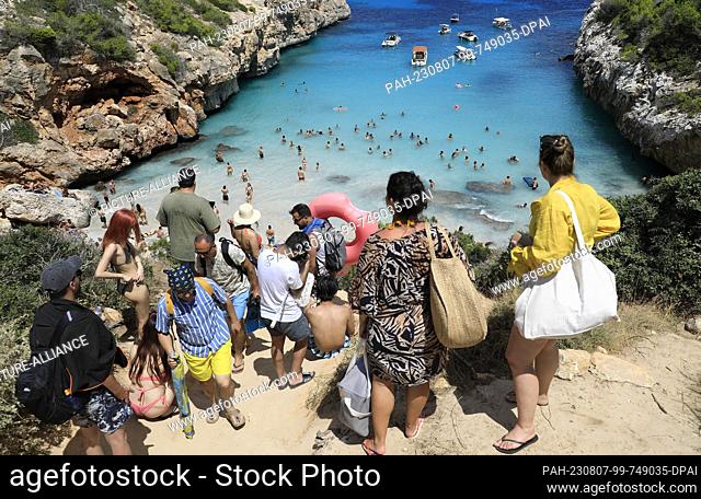 06 August 2023, Spain, Santanyi: People line up at Calo des Moro beach in Mallorca, one of the most crowded beaches in Mallorca