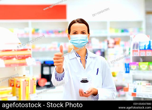 apothecary in mask showing thumbs up at pharmacy
