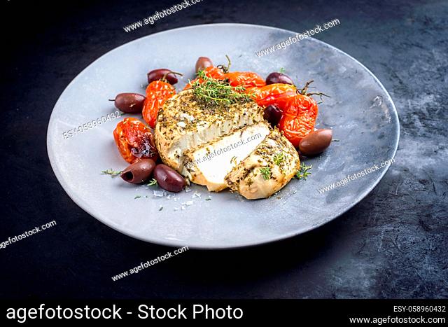Modern style traditional Italian ricotta al forno cake with barbecue tomatoes and Kalamata olives offered as close-up on a design plate