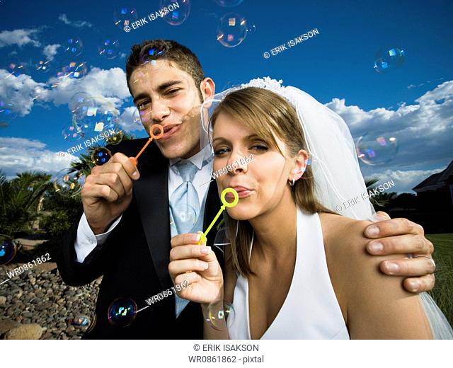 Close-up of newlywed couple blowing bubbles with a bubble wand