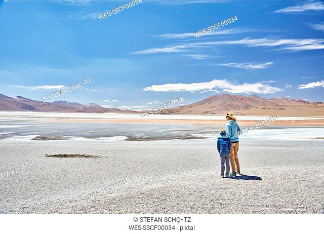 Bolivia, Laguna Colorada, mother and son at lakeshore with view to the Andes