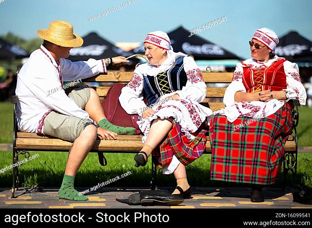08/29/2020 Belarus, Lyaskovichi. Celebration in the city. People in national Slavic clothes are sitting on the bench. Belarusians or ukran man and women