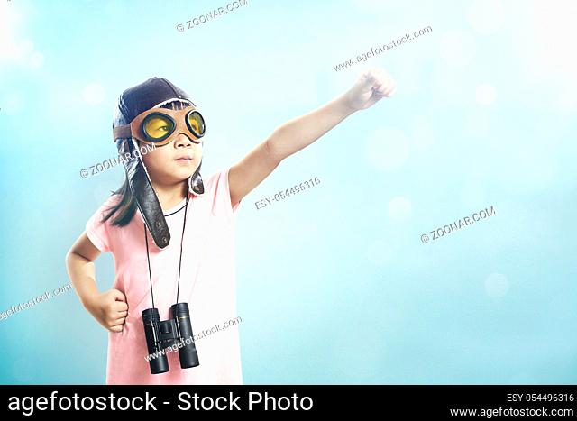 Little asian girl wear aviator glasses and telescope; dreams of becoming a pilot or explorer; Flare and bokeh effect apply with vintage mint green wall...