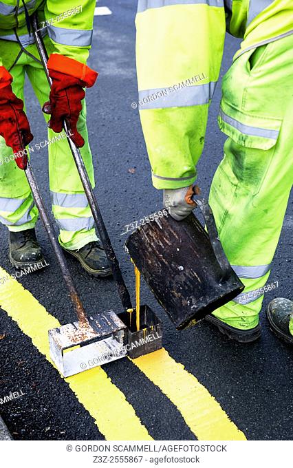 Workmen laying down double yellow lines in Basildon, Essex, UK