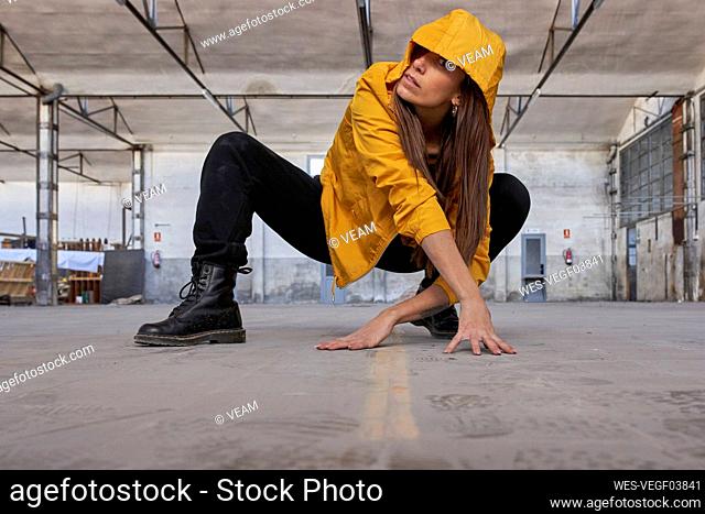 Modern dancer in yellow jacket practicing dance at abandoned factory
