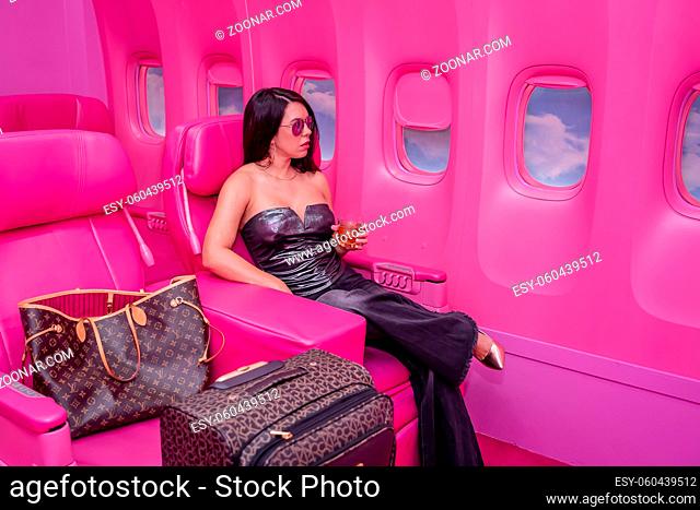 A beautiful asian model sits in a pink airplane ready for her next adventure