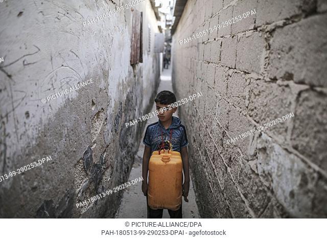 dpatop - A boy hangs a jerrycan from his neck as he plays between the primitive homes of the Palestinian Jabalia refugee camp in Jabalia, northern Gaza Strip