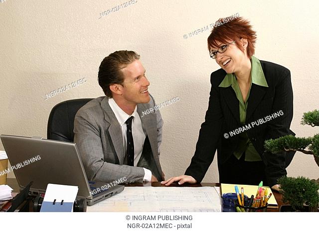 Businessman sitting in an office with his secretary standing beside him