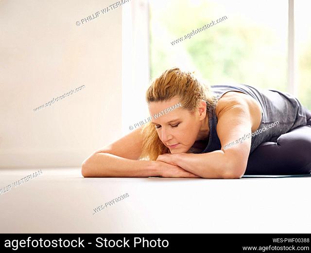 Blond woman with eyes closed doing stretching exercise at home