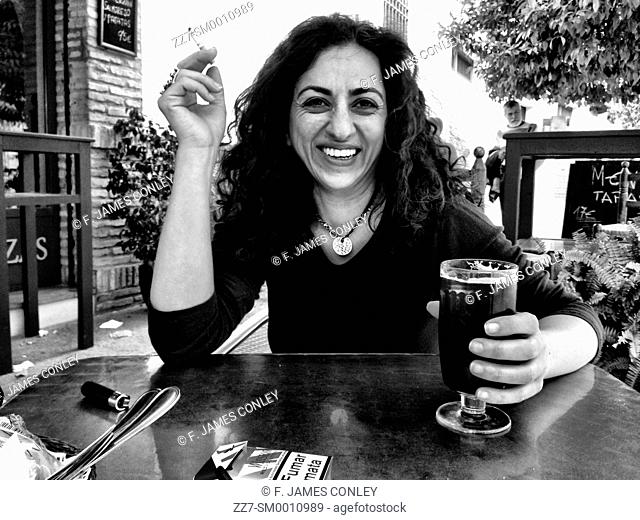A woman enjoys a beer and a cigarette