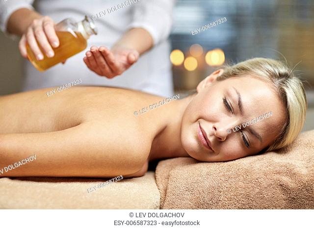 people, beauty, spa, healthy lifestyle and relaxation concept - close up of beautiful young woman lying with closed eyes on massage table and therapist holding...