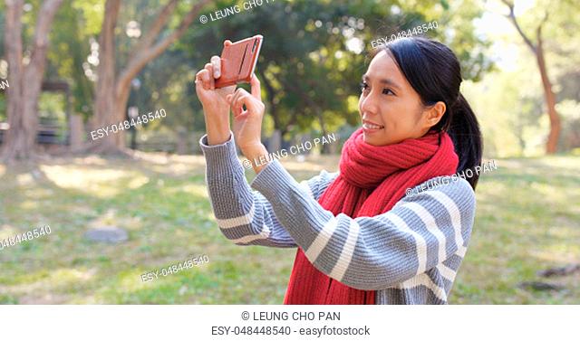 Woman taking photo on cellphone in the park