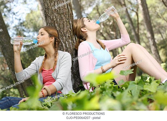 Young women drinking bottled water in forest