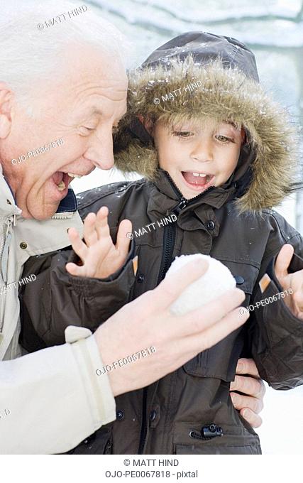 Grandfather giving grandson snowball