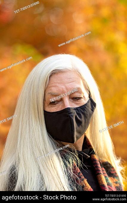 Portrait of senior woman wearing Covid protective mask outdoors in fall