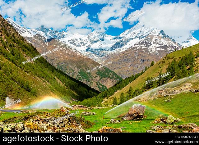 Rainbows in irrigation water spouts in Summer Alps mountain (Switzerland, near Zermatt)