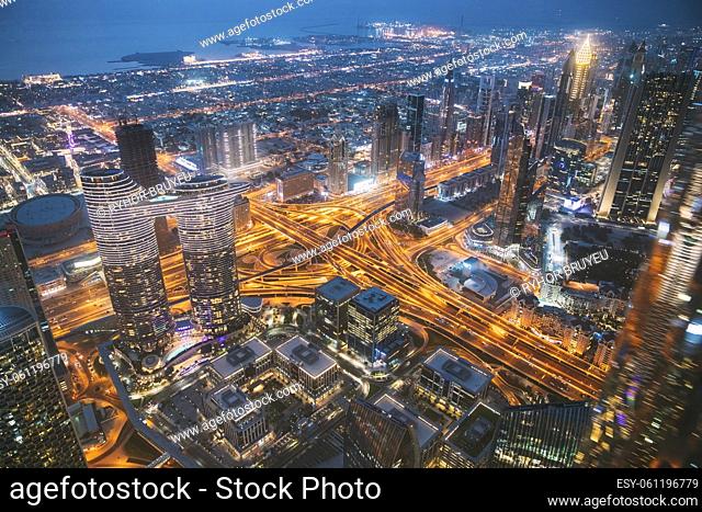 Aerial View Of Evening Night Scenic View Of Skyscraper In Dubai. Street Night Traffic In Residential District. Waterfront And Dubai Cityscape In Summer Evening...