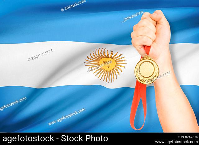 Sportsman holding gold medal with flag on background - Argentine Republic
