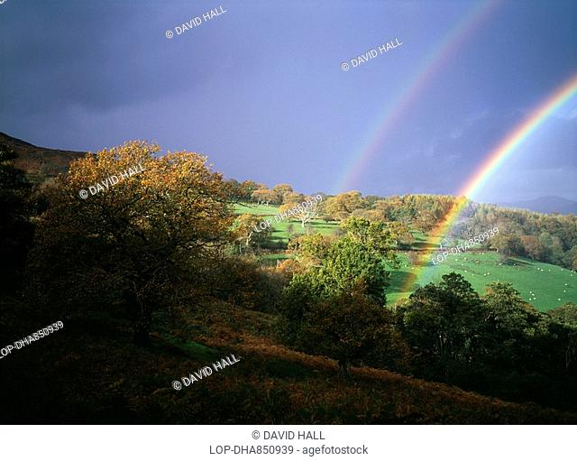 Wales, Denbighshire, Near Llangollen, Storm light with double rainbow against dark skies over Welsh hills