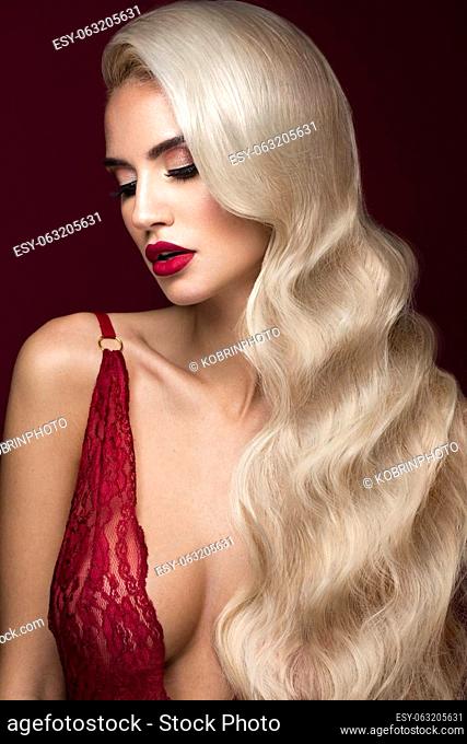 Beautiful blonde in a Hollywood manner with curls, red lips, red lingerie. Beauty face and hair. Picture taken in the studio