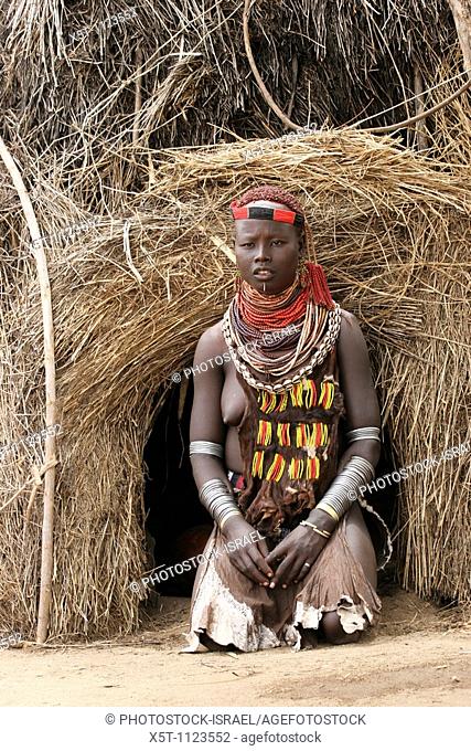 Africa, Ethiopia, Omo Valley, Daasanach tribe woman in front of hut