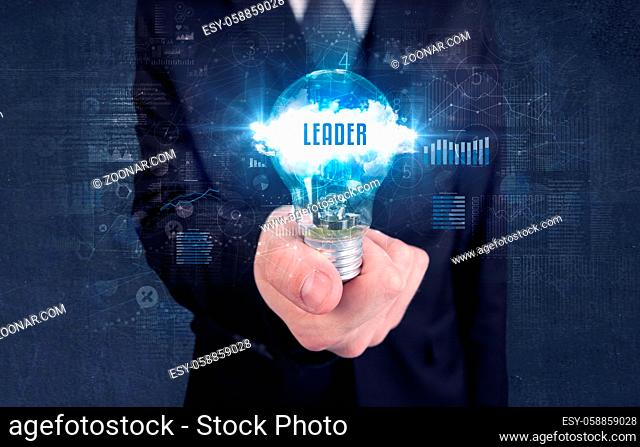 Businessman holding a light bulb with LEADER inscription, new business concept