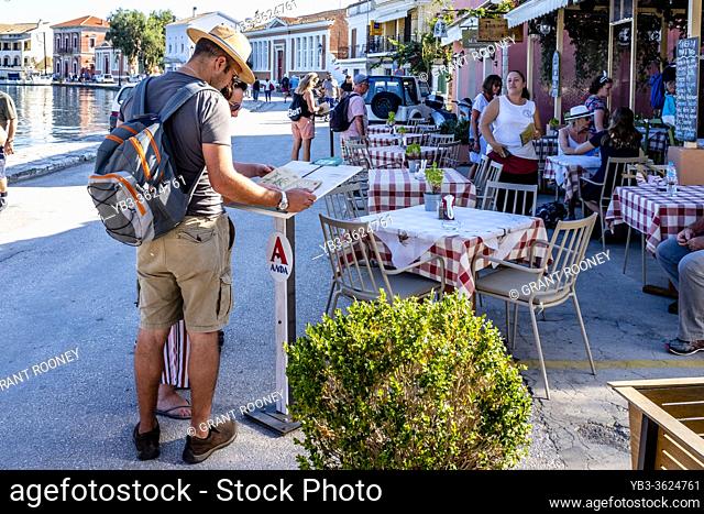 Tourists Looking At A Restaurant Menu, Paxos Island, Greece