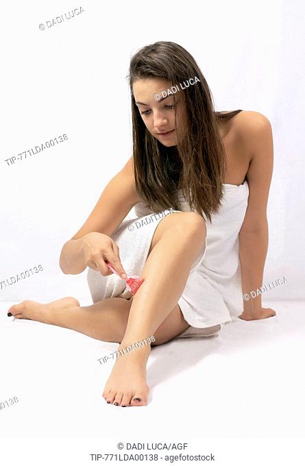 young woman shaving her legs with a razor blade