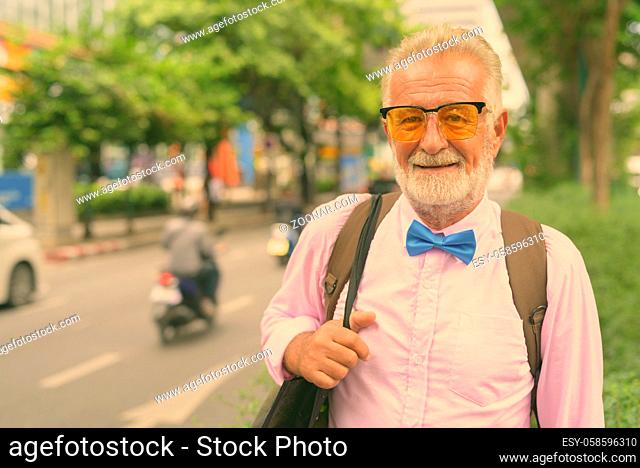 Portrait of handsome senior tourist man wearing stylish clothes while exploring the city of Bangkok