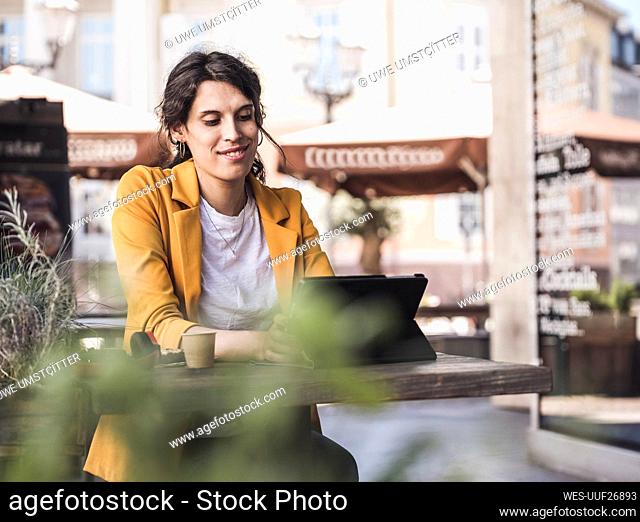 Smiling transgender businesswoman using tablet PC at cafe