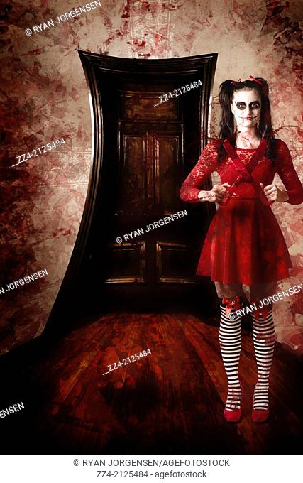 Full length photograph of a creepy woman holding bloody scissors inside dark annals of a haunted house