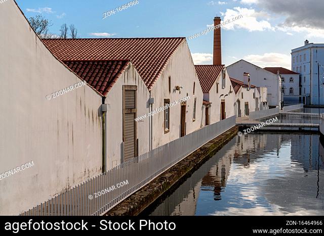Tomar, Portugal: 8 December 2020: row of factory buildings next to a calm river canal