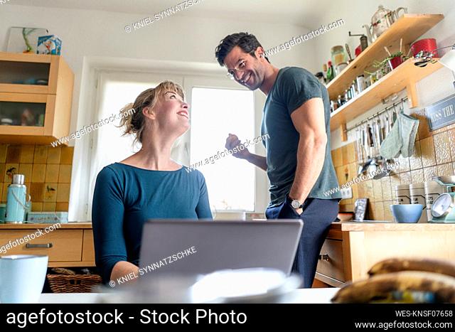 Happy couple in kitchen with laptop